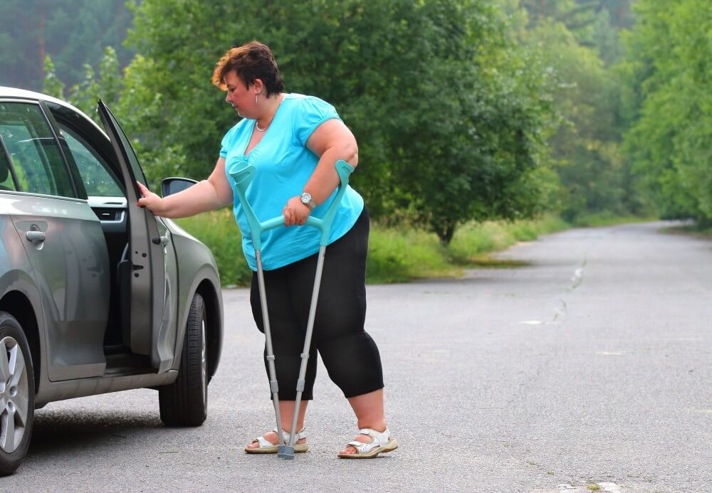 Woman with crutches opening a car door